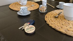 A table set with white and patterned cups, a glass jar, a keychain, and woven placemats. - Almond Tree Suite (Ostuni)