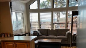 A kitchen with wooden cabinets, a large island, and a view through the windows. - Private Cabin 21 with Jacuzzi and Spacious Deck with View and Outdoor Seating (Private Beach Owned by White Rock Resort) (Smith River)