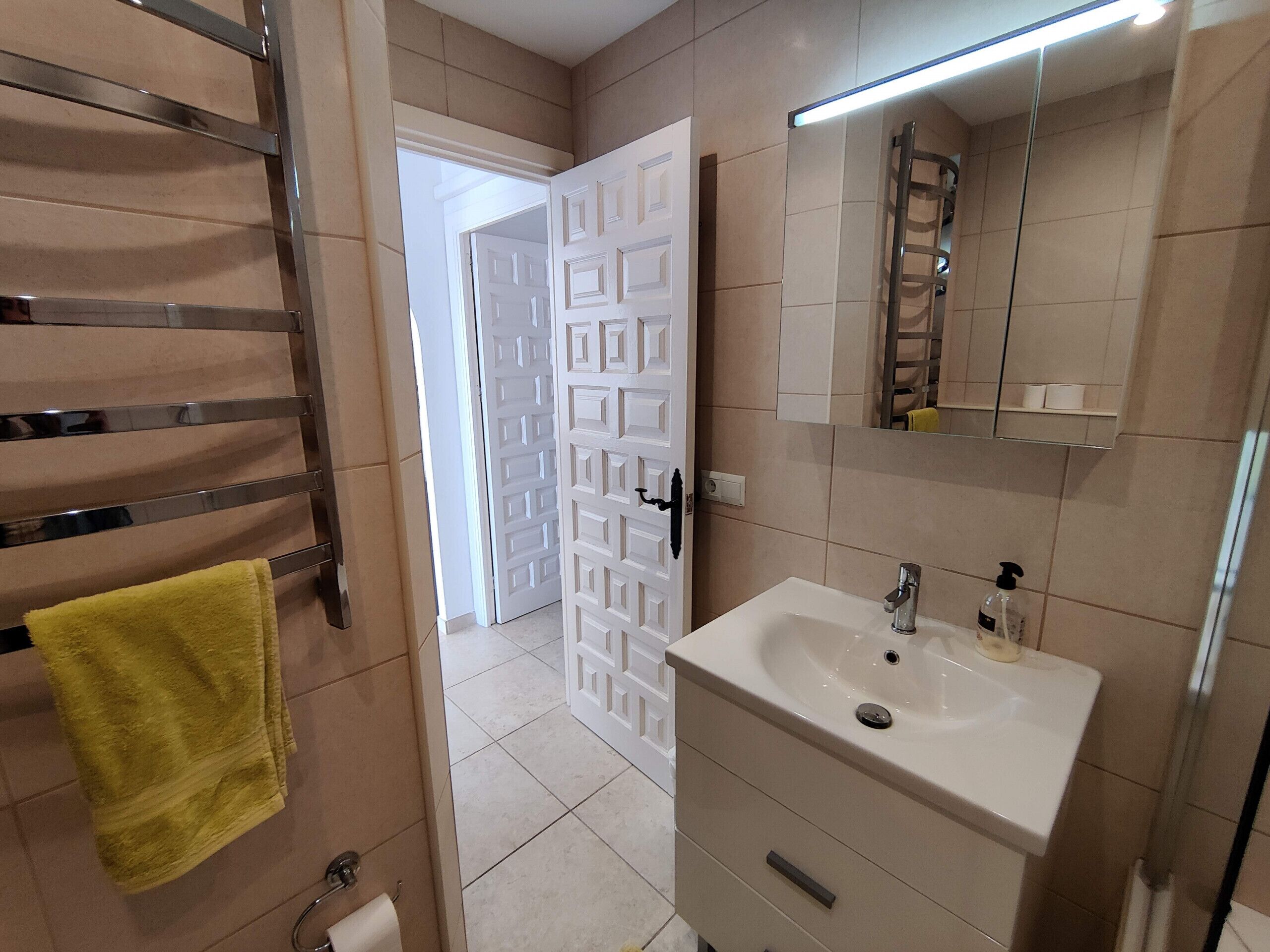 Une salle de bain avec un lavabo blanc, un miroir et un porte-serviettes.