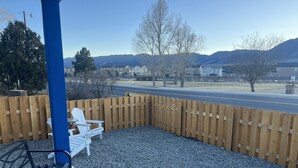 Un patio con una silla Adirondack blanca, un poste azul y una valla de madera.