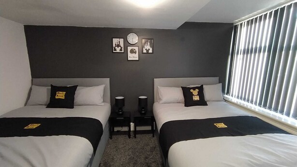Ein Hotelzimmer mit zwei Betten, einer Uhr und gerahmten Bildern an der Wand.