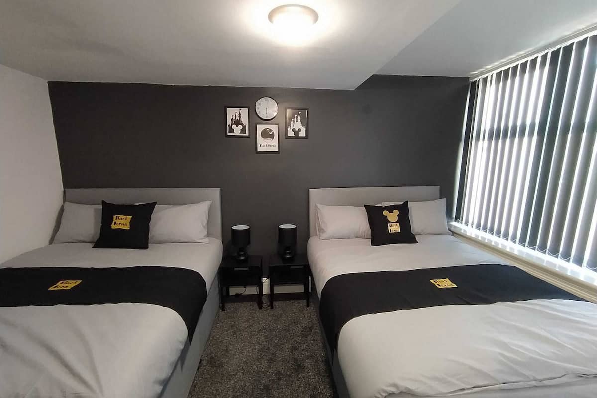 Ein Hotelzimmer mit zwei Betten, einer Uhr und gerahmten Bildern an der Wand.