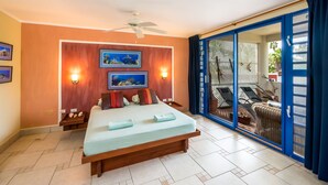 Un dormitorio con cama, luces fijadas a la pared, ventilador de techo y vistas a un espacio exterior con mobiliario.