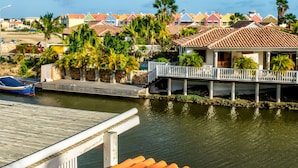 Una propiedad frente al agua con muelle, terraza techada y casas coloridas al fondo.