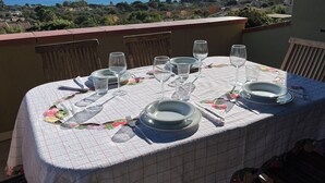 A table set for dining with a view of the sea and a balcony.