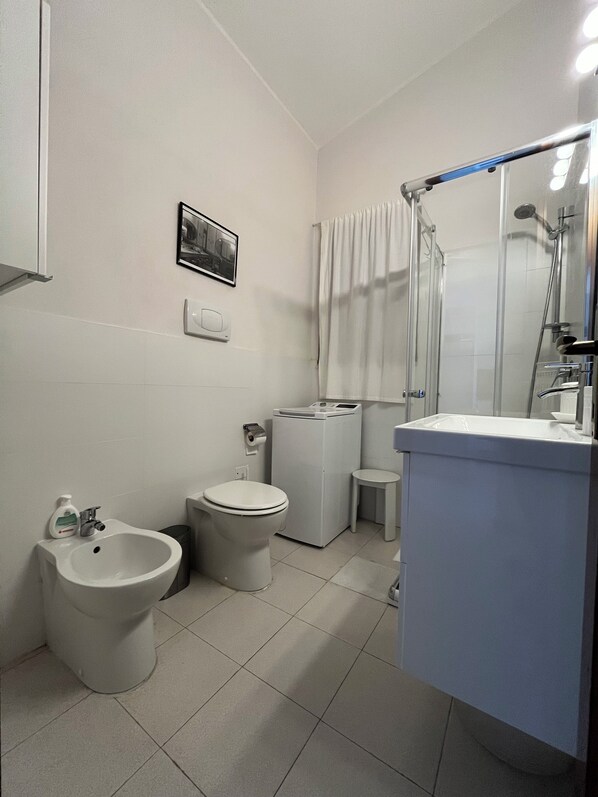 A modern bathroom with a bidet, toilet, and a shower area.