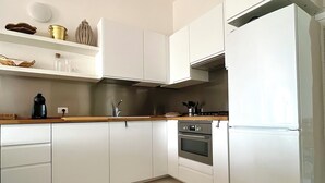 A modern kitchen with white cabinets, a stainless steel oven, and a built-in refrigerator.