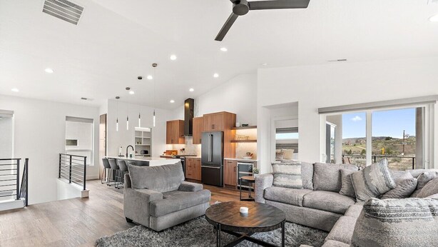 Ein großzügiger Wohnbereich mit einer grauen Sofagarnitur, einem Couchtisch und Blick auf die Küche im Hintergrund.