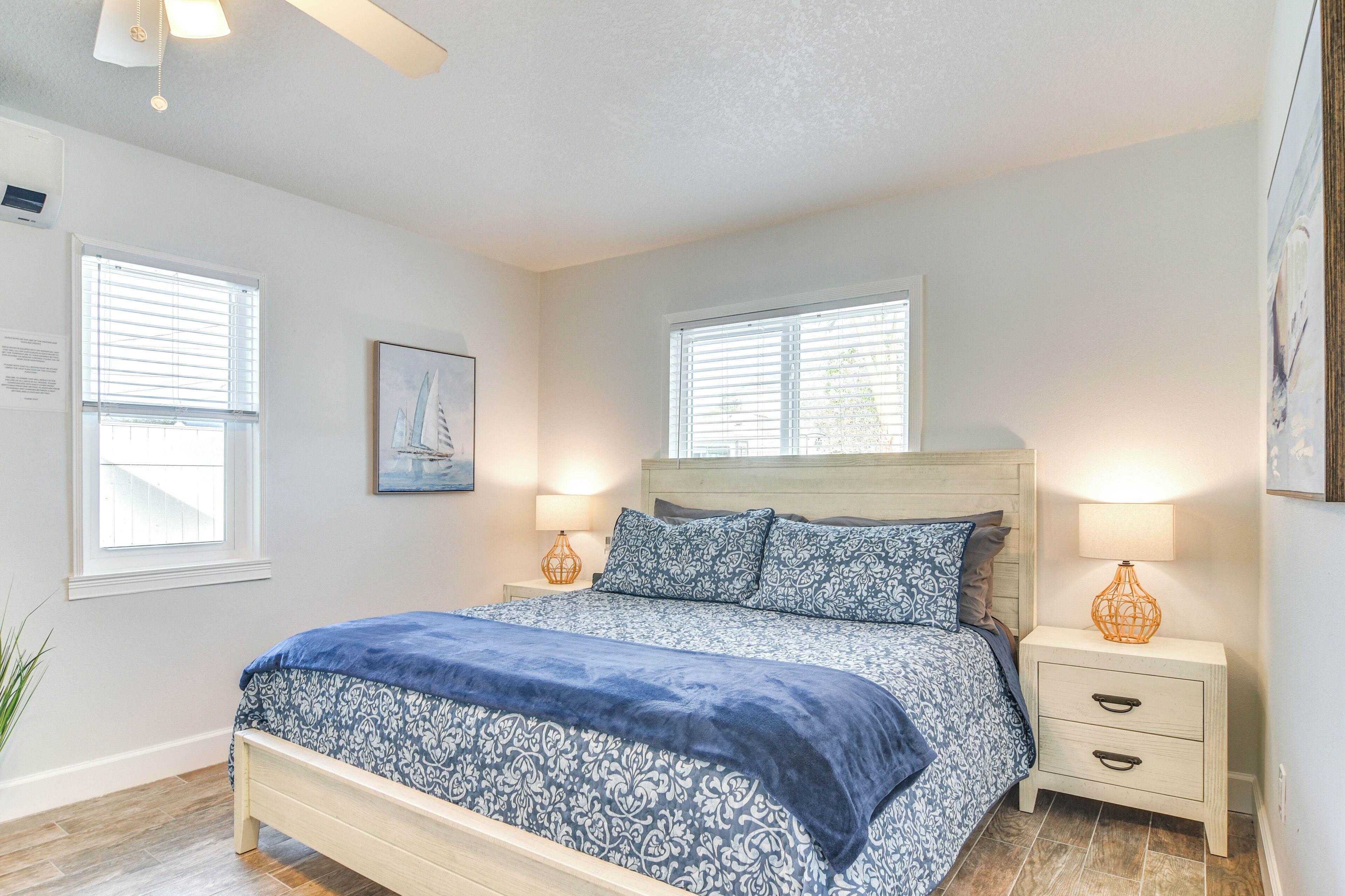 A bedroom with a bed, two bedside tables, a nightstand, and a window.