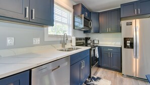 A modern kitchen with dark blue cabinets, stainless steel appliances, and a white countertop.