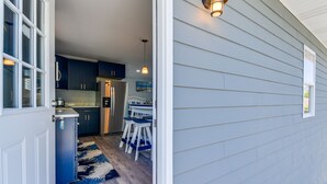 A modern kitchen with dark cabinets, a refrigerator, and a dining area with a table and chairs.