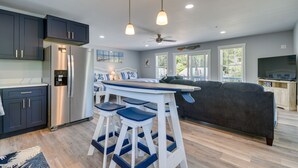 A modern kitchen with dark cabinets, a stainless steel refrigerator, and a bar area with stools.