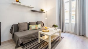 Uma sala de estar moderna com um sofá, uma mesa de centro e uma janela com cortinas.