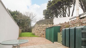 A patio area with a table and chairs, a stone wall, and a green fence. - 78 King Street (Wexford)