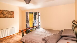 A bedroom with a bed, a radiator, a map on the wall, and a window with curtains. - 78 King Street (Wexford)