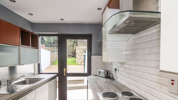 A modern kitchen with a built-in stove, a sink, and a window overlooking a garden. - 78 King Street (Wexford)