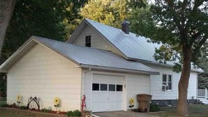 A single-story house with a garage, surrounded by trees and a well-maintained lawn.