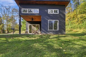 A modern two-story house with a covered patio, large windows, and a view of the surrounding trees. - Onyx - Near Hocking Hills (Rockbridge)