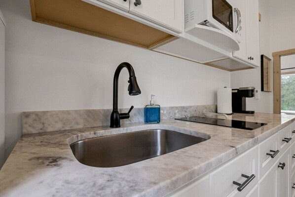 A modern kitchen with a stainless steel sink, black faucet, and white cabinets.