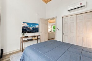 A bedroom with a bed, a TV on the wall, a wooden desk, and a door leading to another room. - Onyx - Near Hocking Hills (Rockbridge)