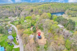 An aerial view of a property with a small house surrounded by trees and a lake.