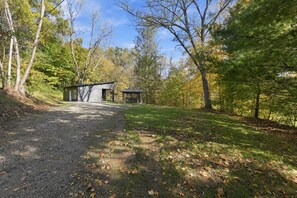 A gravel path leading to a small cabin with a metal roof and a wooden door, surrounded by trees and grass. - Onyx - Near Hocking Hills (Rockbridge)