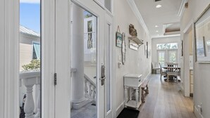 A hallway with a white door, a small table, and a bench. - 4BR Spacious Beach Home with Private Pool+ Studio Apartment | Southern Nights (Destin)