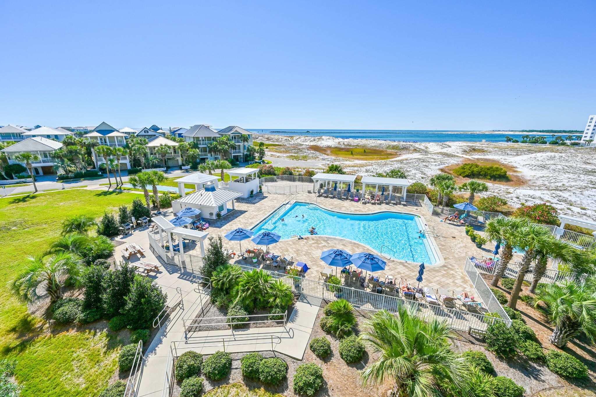 A resort with a central swimming pool, outdoor seating, and a beach view.