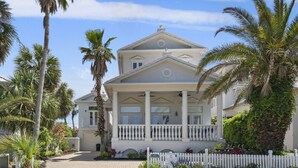 A two-story house with a white facade, a balcony with white railings, and a white picket fence. - 4BR Spacious Beach Home with Private Pool+ Studio Apartment | Southern Nights (Destin)