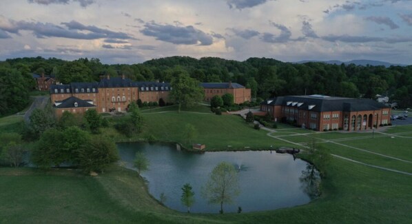 A large brick building with multiple wings, a central courtyard, and a small pond.