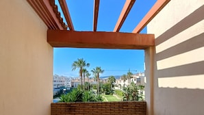 A balcony with a view of a residential area, including houses and palm trees. - 154 Casa Lelik (Tarifa)