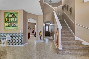 Staircase leads to a stylish living space with a carpeted staircase, framed artwork, and patterned tile backsplash.