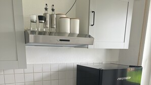 A compact kitchen with a black refrigerator, a built-in oven, a stainless steel sink, and a wooden countertop. - Wunderschöne 1-zimmer Wohnung (Wiesbaden)