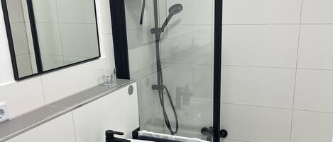 Un baño moderno con lavamanos blanco, cabina de ducha de vidrio y bañera.