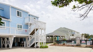 A beachfront property with a blue building, a covered patio, and a fenced swimming area. - Top floor ocean front condo in Ocean Dunes! (Kure Beach)
