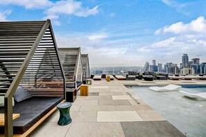 Enjoy panoramic views of the city skyline from our rooftop terrace, featuring lounge areas with sofas and chairs, and a small pool.