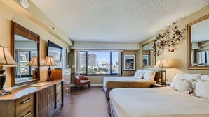 A hotel room with a large bed, a smaller bed, a desk with a chair, a dresser, and a large window offering a city view. - Outstanding Location | 1BR Haven near the Strip (Las Vegas)