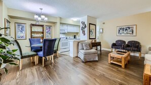 A spacious living area with a dining table, chairs, a sofa, and a coffee table. There is a kitchen area with cabinets and a microwave. - Outstanding Location | 1BR Haven near the Strip (Las Vegas)