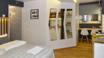 A modern hotel room with a bed, a desk, and a bathroom.