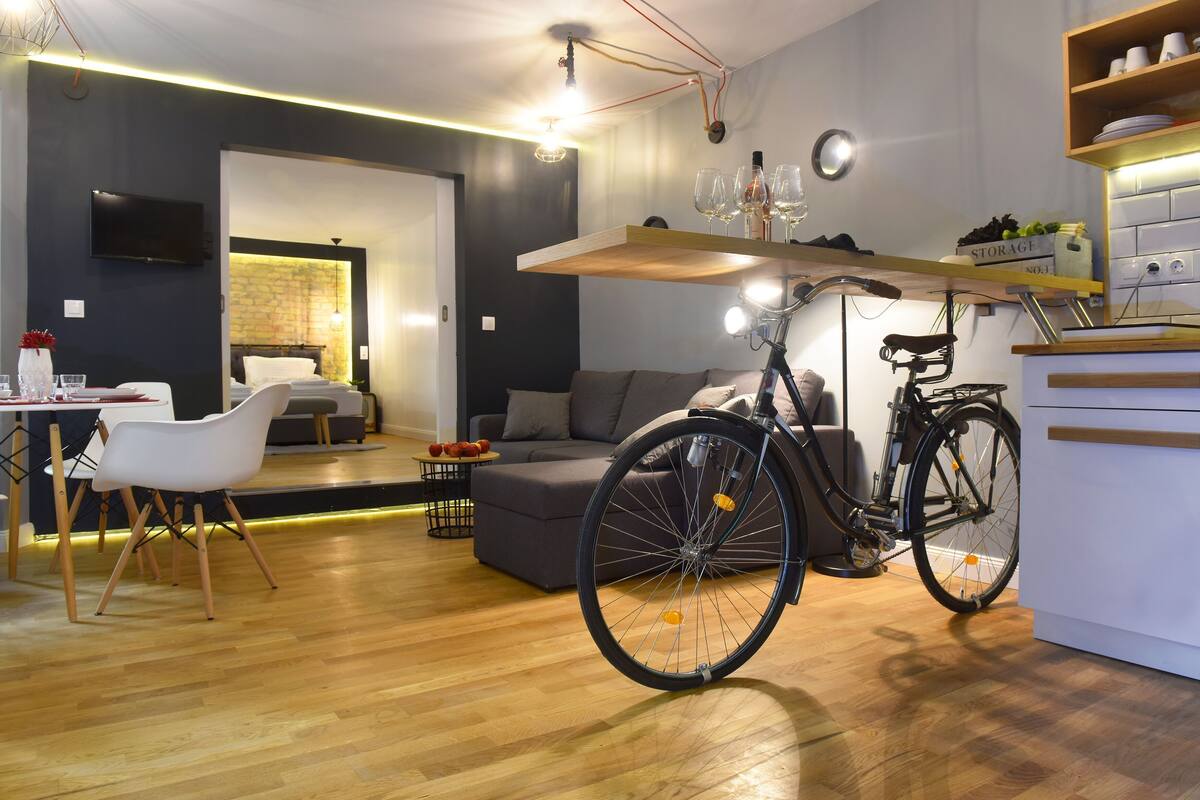 Un espacio habitable moderno con zona de comedor, sofá, bicicleta y área de cocina.