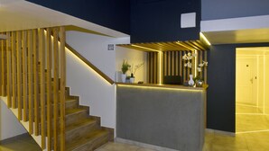 A modern reception area with a wooden staircase, a reception desk, and potted plants. - Walk Inn Váci 78 (Budapest)