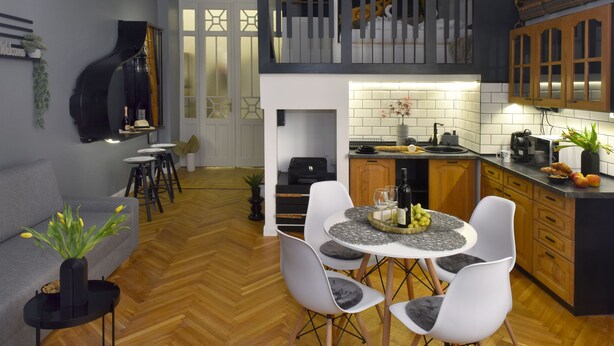 A modern kitchen with a dining area, a staircase leading to an upper level, and a piano in the living area. - Walk Inn Váci 78 (Budapest)