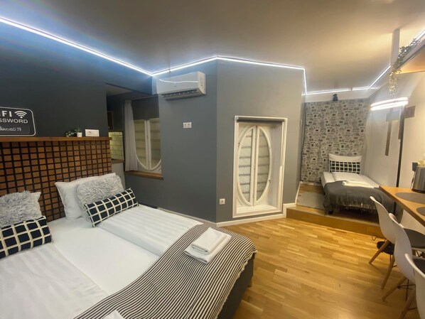 A hotel room with a bed, bedside table, chair, desk, and a small kitchenette. - Walk Inn Váci 78 (Budapest)