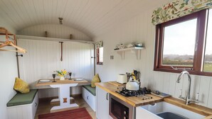 Une cuisine de taille réduite, dotée d’un plan de travail en bois, d’un évier, d’une cuisinière et d’une fenêtre donnant sur l’extérieur.
