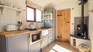Une cuisine équipée d’un poêle à bois, d’un four encastré et d’une fenêtre située au-dessus de l’évier.
