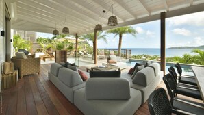 Un espace extérieur abrité, doté d’une piscine, de chaises longues et offrant une vue sur l’océan.