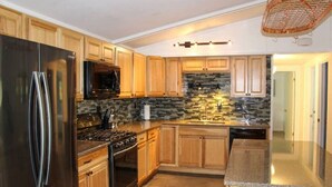 Una cocina moderna con armarios de madera, un refrigerador de acero inoxidable, un microondas y una estufa a gas.
