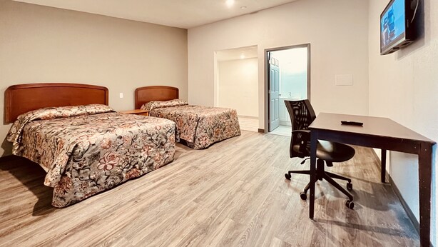 Una habitación de hotel con dos camas, un escritorio y un televisor.