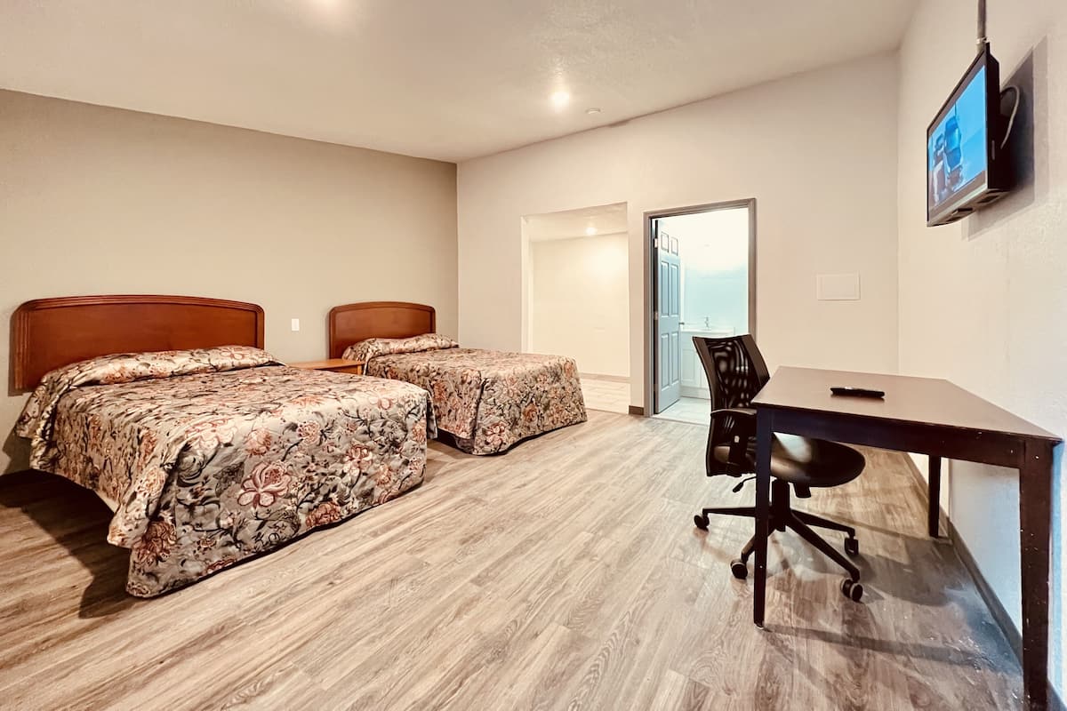 Une chambre d’hôtel avec deux lits, un bureau et une télévision.