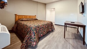 Un dormitorio con cama, escritorio y televisión.